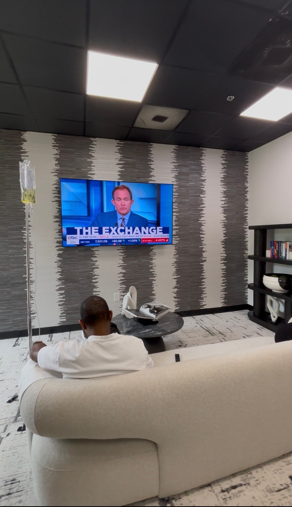 Client relaxing on a couch with an IV drip while catching up on the news