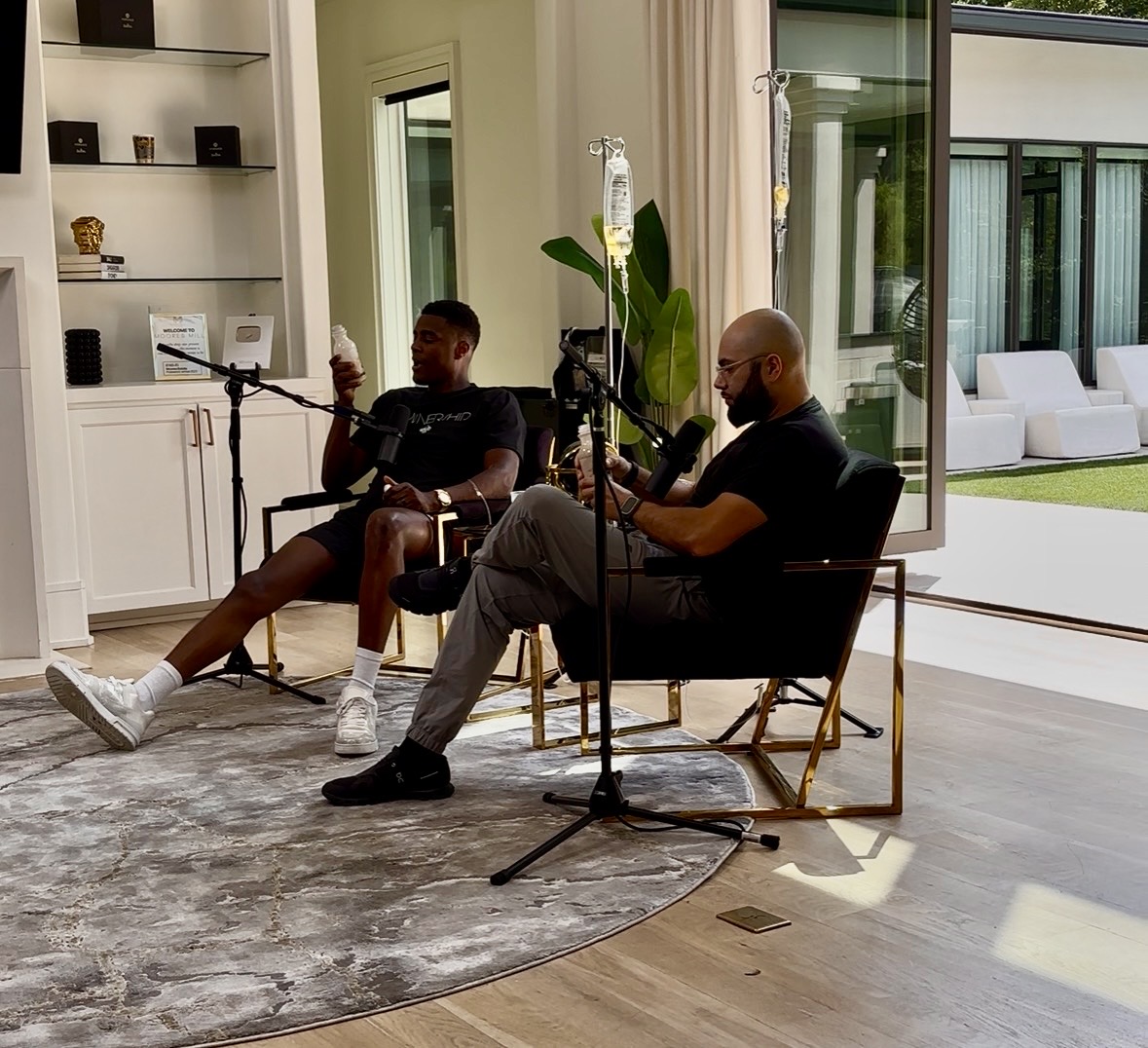 Two creators recording a podcast while receiving IV hydration